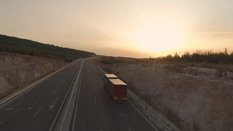 Drone chasing big truck with trailer driving on empty highway at sunset time Stock Footage 158979093