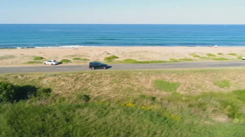 Drone chasing fast driving black SUV along coastal asphalt road with crashing Vídeo Stock 135224016
