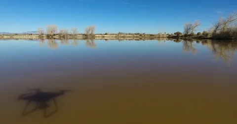 Drone chasing shadow over a reflective pond 4k 24fps Stock Footage 72192287