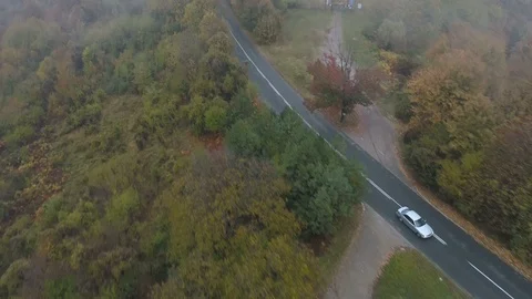 Drone chasing white car driving on misty asphalt road in the mountains Stock Footage 119310678