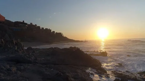 Drone cinematic drone push in to sunset over rocky seashore with waves breaking Stock Footage 104888150