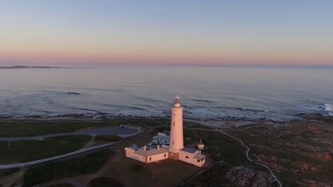 Drone circles around Cape Saint Francis lighthouse during golden sunset Video stock 85158232