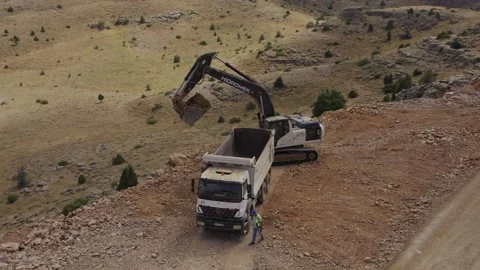 The drone circles around an excavator as it loads excavated earth into a truck. Stock Footage 247641832