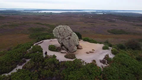 Drone circles boulder on heath as two walkers approach it - Agglestone Rock Stock Footage 146880275