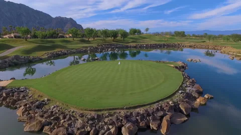 Drone circles hole on golf course on island with desert mountains Stock Footage 167142722