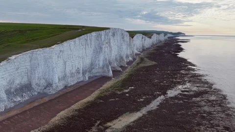 Drone circling around towering white cliff on calm coastal edge Stock Footage 309765253