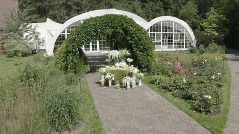 Drone circling decorative setup beneath green arch Stock Footage 329540277