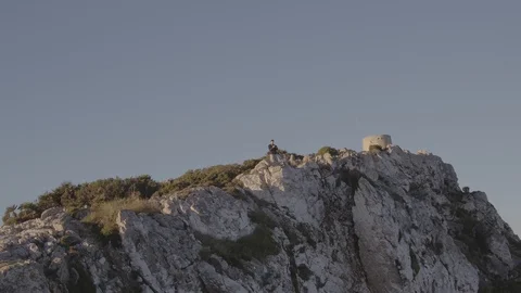 Drone circling guy with camera on cliff top going down Stock Footage 101427615