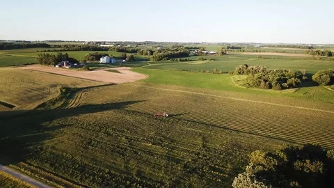 Drone circling Iowa farmer cutting hay mid summer at sunset Stock Footage
