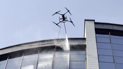 Drone is cleaning windows. Drone spraying water onto windows of building Stock Footage 338171915