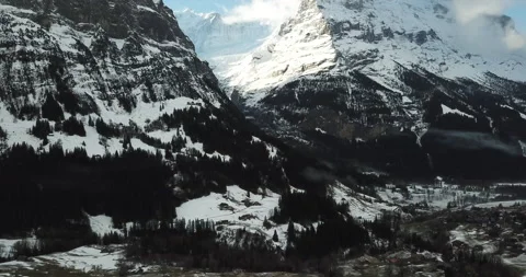 Drone climbing higher over alpine town with snow topped mountains chalets Stock Footage 140341865