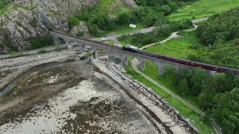 Drone close view of Jacobite steam train crossing Lochailort viaduct Stock Footage 330591623