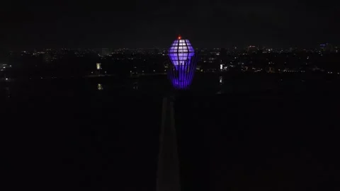 Drone continuously orbits blue-purple gem atop colorfully lit up bridge Stock Footage 342255879