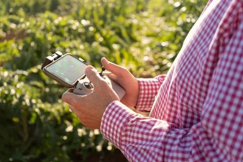Drone control pad with a smartphone on a stand being used by the hands of a.. Stock Photos