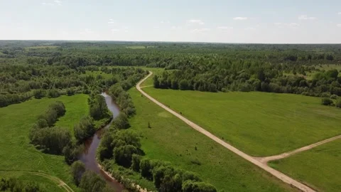 Drone Country Road through a Field along a Stream Stock Footage 134138564