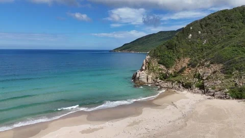 Drone crossing wild beach toward rocky cape revealing hidden coastline 動画素材 336974601