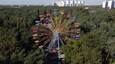 A drone departs from a rotating Soviet Ferris wheel in a beautiful green park Stock Footage 145058307