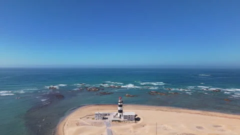 Drone Descending with View of Lighthouse, Ocean, Beach, Sand, Blue Sky, and Wave Stock Footage 306284821