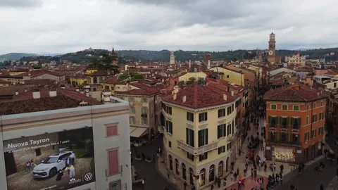 Drone descends and pulls away over Via Mazzini and Piazza Bra rooftops in Vídeos de archivo 312715695