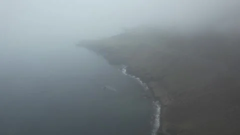 Drone descent over rocky coast and road in dense fog, Breiddalsvik Iceland Stock Footage 346551639