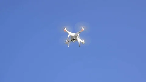 Drone DJI Phantom 4 in flight. Quadrocopter against the blue sky with white Stock Footage 85148459