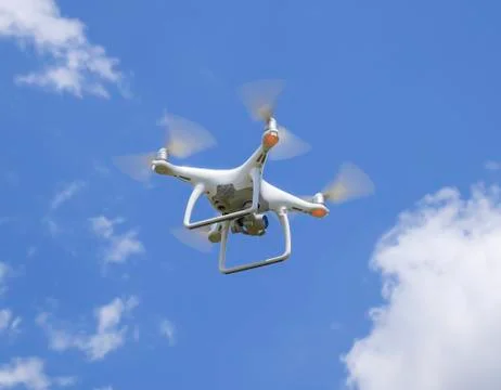 Drone DJI Phantom 4 in flight. Quadrocopter against the blue sky Stock Photos