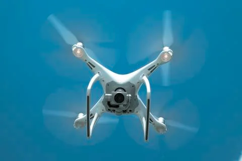 Drone DJI Phantom 4 in flight. Quadrocopter against the blue sky Stock Photos
