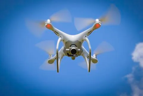 Drone DJI Phantom 4 in flight. Quadrocopter against the blue sky Stock Photos