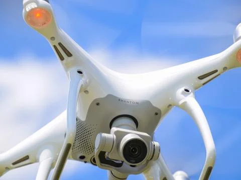 Drone DJI Phantom 4 in flight. Quadrocopter against the blue sky with white c Stock Photos
