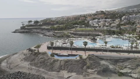 Drone does 360 around large pool next to Playa de Fanabe beach in Costa Adeje Stock Footage 312882457