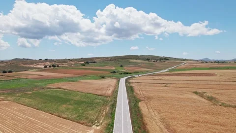 Drone dolly above empty grey asphalt road between grassland farm plots 스톡 동영상 256063427