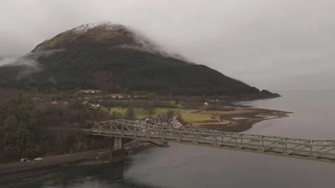 Drone dropping over loch &amp; bridge with misty mountain in background 4K Stock Footage 299326999