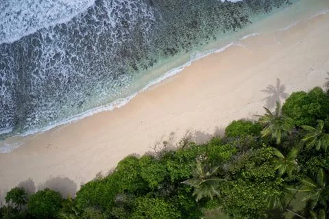 Drone field of view of waves along empty beach Praslin Seychelles. Stock Photos