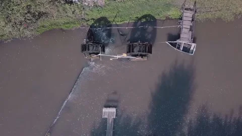 The drone is filmed over the river on which there is a water mill, a pier and a Video stock 143314751