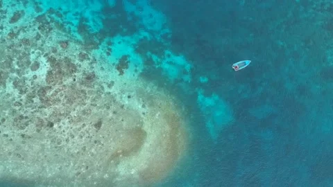 Drone, flat blue ocean with a small dingy and coral reef Stock Footage 130313626