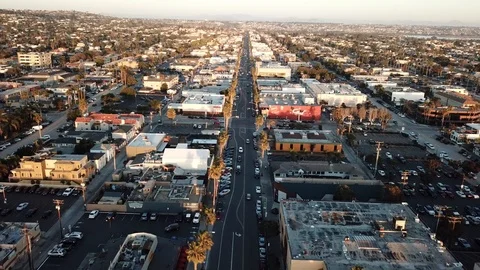 Drone flies at 100 feet down a sleepy beach town boulevard lined with palm trees Stock Footage 86129762