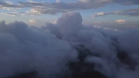 Drone flies above the clouds in the mountains and slowly reveals the ridge Stock Footage 93043888