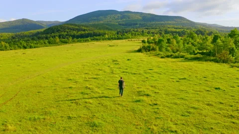 Drone flies above guy walks on grassland Stock Footage 138752174