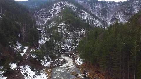 Drone flies above mountain stream flowing through woods in snow 스톡 동영상 263239221
