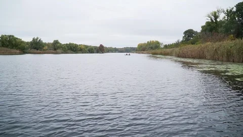 Drone flies above surface of river towards small boat with two fishermen in it Stock Footage 263130798