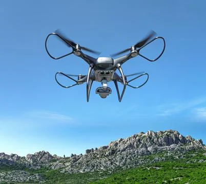 A drone flies against the backdrop of a mountain landscape. Stock Photos