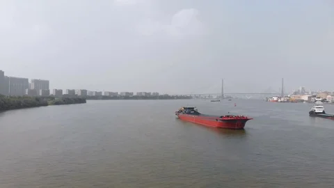 A drone flies along a large red cargo ship over a river. Video stock 117922437