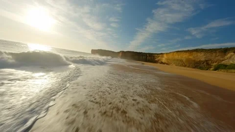 A drone flies along the ocean with waves at sunset next to a rock in Australia Stock Footage 237398170
