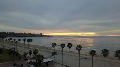 Drone flies up and back over palm lined Southern California beach as night falls 库存影片 87959671