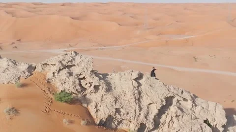A drone flies around a bearded man dressed as a shaman who prays on a cliff in Stock Footage 250160601