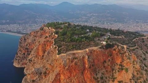 Drone flies around the castle standing on a cliff in Alanya at sunset Stock Footage 240001006