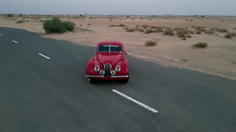 A drone flies around an expensive red vintage car standing on an empty road in Stock Footage 255869503