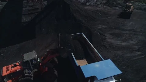 The drone flies around with a heavy dump truck into which the loader fills coal Stock Footage 169589938