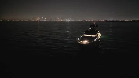 A drone flies around an illuminated expensive private yacht standing at night Stock Footage 248430976