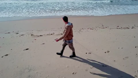 A drone flies around a man on the beach Stock Footage 231346132